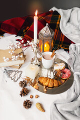 Still life with delicious Christmas gingerbread and cookies  breakfast on a tray in bed , donuts and croissants , cup of cacao or latte with cinnamon, ginger biscuits figure, Christmas candles.