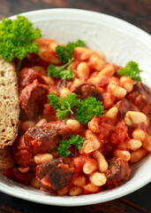 Bean and chorizo stew served in white bowl with parsley