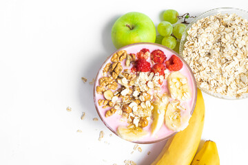 Yogurt with muesli and raspberries. Oatmeal is scattered on the table, ripe banana, nuts, apple, grapes on a white table. copy space. The concept of healthy food, diet, healthy breakfast.
