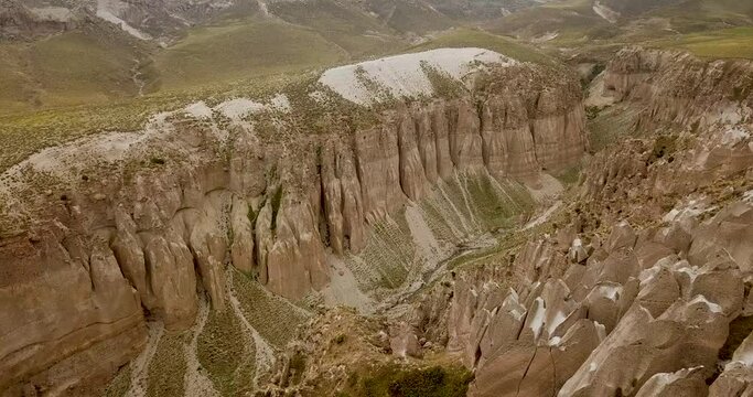 Pillar brown stone cliff column near a little beautiful lake on green mountains hills in Ardabil Sabalan Iran natural landscape wonders