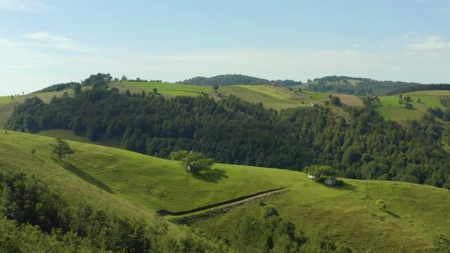 Aerial shot Serbia. drone flight in the mountains where you can see a small house surrounded by fields, forest, mountain peaks and beautiful landscape.
