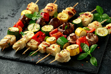 Grilled Halloumi cheese skewers with vegetables on rustic stone board