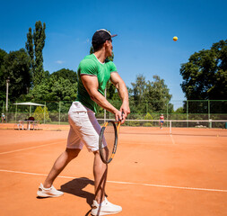 Young athletic man playing tennis on the court.