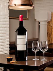 Wine bottle with white label for text with wine glasses and olives and almonds, on top of the...