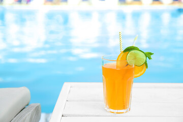 Refreshing cocktail near outdoor swimming pool on sunny day. Space for text