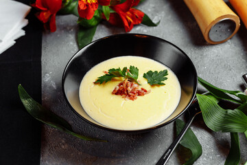 bowl of tasty cheese cream soup with bacon on a gray background