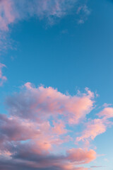 blue sky and fluffy pink clouds at sunset, vertical format and copy space