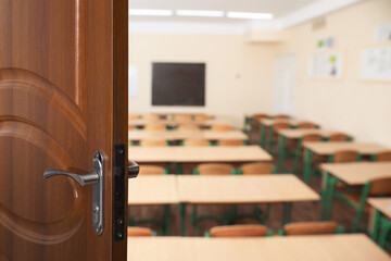 Wooden door open into modern empty classroom