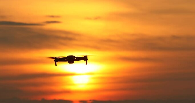A silhouette of a drone flying in a beautiful sunset, drone in the sunset sky,A drone taking pictures of aerial views