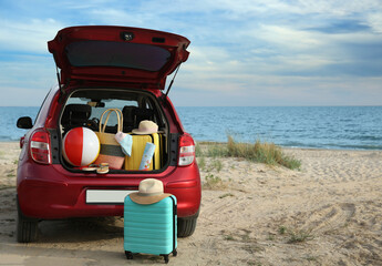 Red car luggage on beach, space for text. Summer vacation trip
