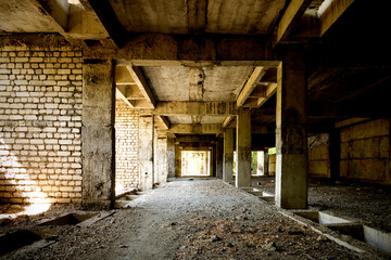 Fototapeta na wymiar Unfinished and abandoned concrete and brick building. Unfinished construction with harsh sun light and shades.