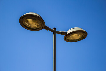 Poste de iluminação pública com céu azul ao fundo.
