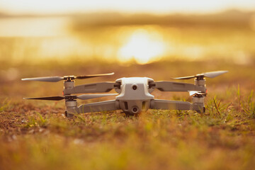 The drone is parked on the ground, drone parked on the grass during sunset.drone is off lying on the ground