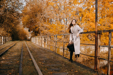 beautiful long-haired woman walks through the autumn streets. Railway, autumn, woman in a coat.