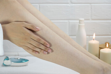 Fototapeta premium Skin care, body. Preparing legs for the procedure of hair removal. Hair on the legs of women. Body positive, self-acceptance, feminism. Apply the cream, massage. Strawberry legs, keratosis. Relaxation