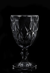 Black faceted wine glass on black background, close up