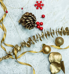 goldene Weihnachtsdekoration auf marmoriertem Hintergrund, festlich arrangiert mit roten Details