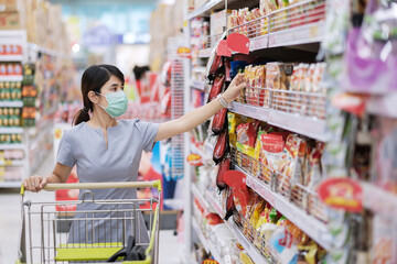 Young woman wearing protective face mask and  shopping in grocery or department store protect...