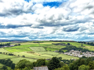 Fototapeta na wymiar Landscape view, from Black Moor Road, looking toward Haworth, with trees, meadows, and a cloudy sky in, Haworth, Bradford, UK