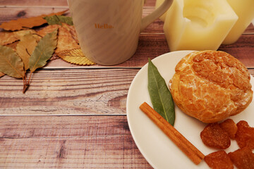 Cup of coffee with piece of sweet and cinnamon on wooden table. Autumn leaves. 秋の紅葉と木製テーブル上のスウィーツ