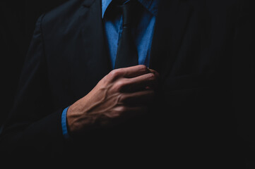 handsome confident businessman wearing and adjusting the black suit