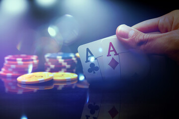 Man's hand holding two aces while playing poker