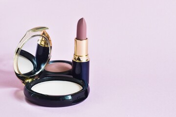 Makeup cosmetics. Pink matte lipstick, powder and blush on a pink background. Beauty industry...