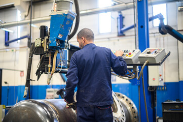 Fototapeta na wymiar Worker operating an automatic welding machine in an industrial plant