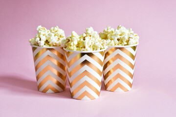 Glasses with popcorn on a pink background.
