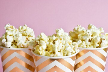 Glasses with popcorn on a pink background. Close up, copy space.
