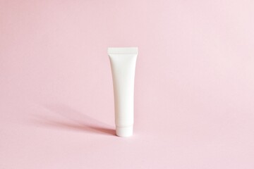 White cosmetic products tube. Blank plastic container for cream, lotion, toothpaste, nourishing or moisturizing mask on a pink background. Eco-friendly, organic cosmetology concept. Copy space.