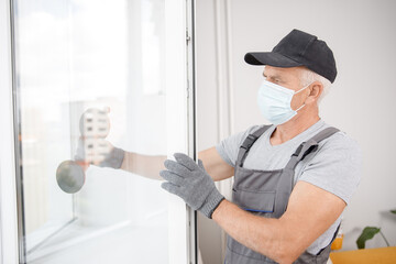 Naklejka na ściany i meble Worker man installs plastic windows and doors with double-glazed white