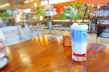 Fresh blue milk juice over coconut milk with ice in glass on wood table. The blue milk is popular menu for order. The taste is delicious. Close up.