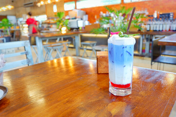 Fresh blue milk juice over coconut milk with ice in glass on wood table. The blue milk is popular menu for order. The taste is delicious. Close up.