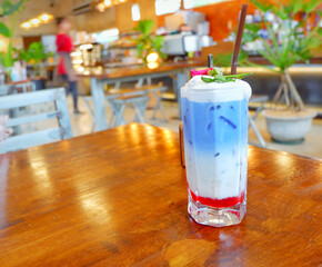 Fresh blue milk juice over coconut milk with ice in glass on wood table. The blue milk is popular menu for order. The taste is delicious. Close up.