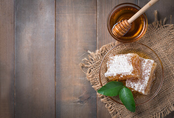 Fototapeta na wymiar Honeycomb on dish with leaf and honey dipper on wood background