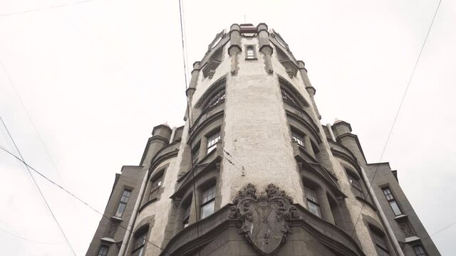Bottom view on tower of old building on background of cloudy sky. Action. Old white stone building is architectural monument of city of Saint Petersburg. Historical architectural landmark