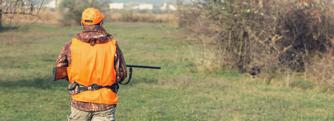 Hunter man in rural field with shotgun and backpack during hunting season
