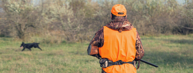 Hunter man in rural field with shotgun and backpack during hunting season