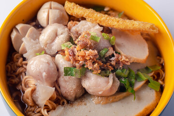 Instant noodles with fish kiew, pork balls and wonton plates. Thai food on a white background.