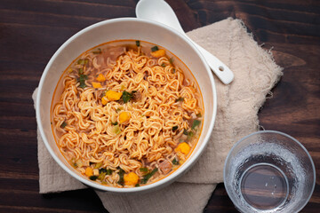 Tom Yum instant noodles in a white ceramic cup on a wooden floor