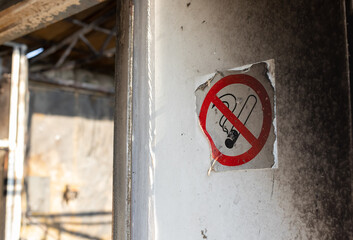 No smoking sign on a room wall with traces of black soot from a fire. violation of fire safety rules. side view.