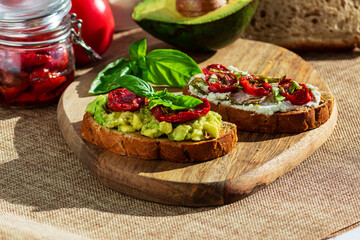 Sandwich with sun-dried tomatoes, avocado, basil, curd cheese on croutons. Vegetarian breakfast or snack