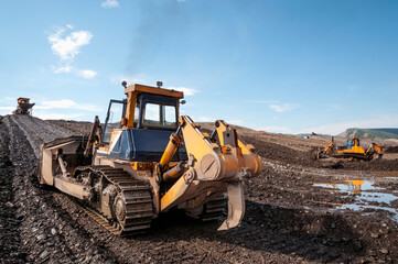 Bulldozers in mountainous wooded areas, layer by layer, remove mountain soil from the surface and shovel it to the side.