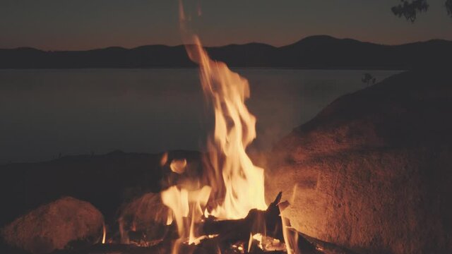 A fire in a fireplace on the lake shores, during the night.