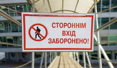 Obraz premium Warning sign No unauthorized entry written in red text in Ukrainian on a white rectangular table. The sign prohibits the passage of strangers.