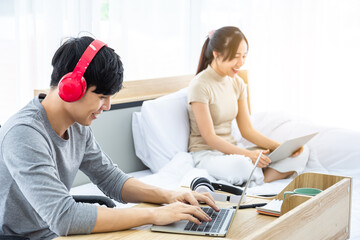 A man working with notebook wearing a bluetooth headphones to listen chatting with colleagues. His...