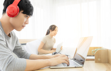 A man working with notebook wearing a bluetooth headphones to listen chatting with colleagues. His...