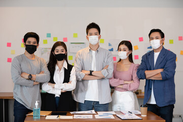 Fototapeta na wymiar Group of Asian business men leader standing wearing mask smile cross arm confidence with Business team at Co-Working space Due Covid-19 flu pandemic and protection,Small Business Startup Concept