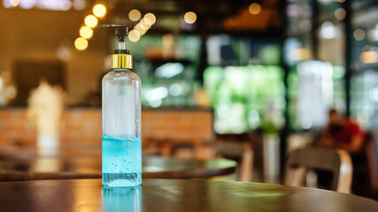 Blue alcohol gel bottle for hand cleaning to prevent the spreading of the Coronavirus (Covid-19), Placed on table to service for customers in the cafe. Healthcare concept. New normal lifestyle